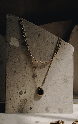 Classic gold necklace with a subtle pendant resting on a polished wooden surface.