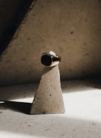 Close-up of a sleek black onyx ring resting on a white marble surface with a hint of red fabric in the background.