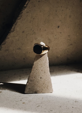 Minimalist ring with engraved mystical symbols resting on a smooth dark stone surface.