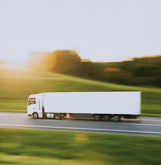 a white semi truck driving down a rural road