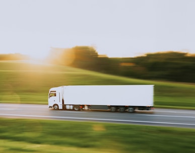 a white semi truck driving down a rural road