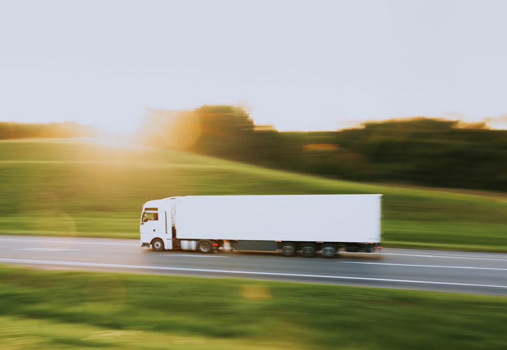 a white semi truck driving down a rural road