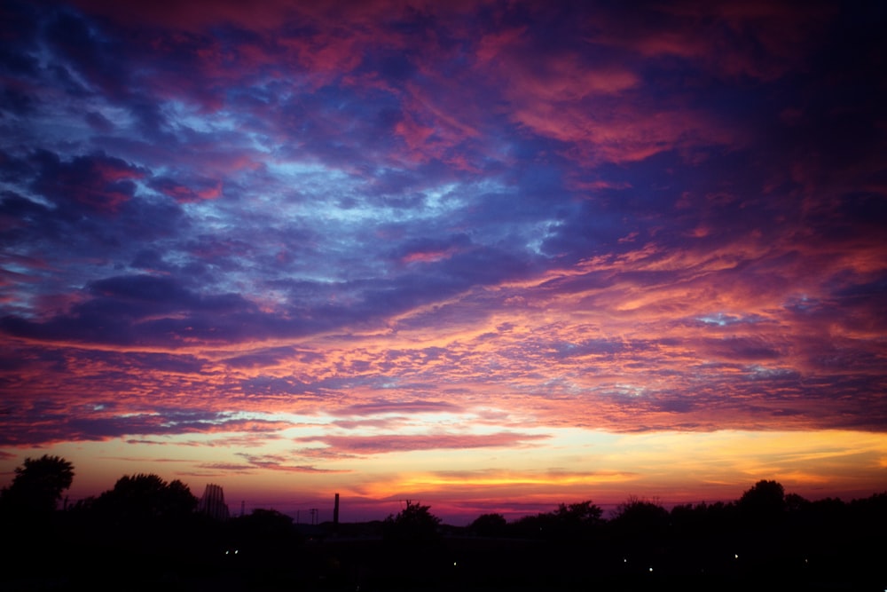 a sunset with clouds and trees in the background