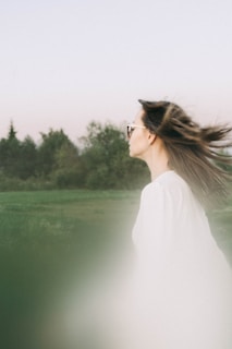 Side profile of a model in a flowing emerald green dress captured during a gentle breeze outdoors.