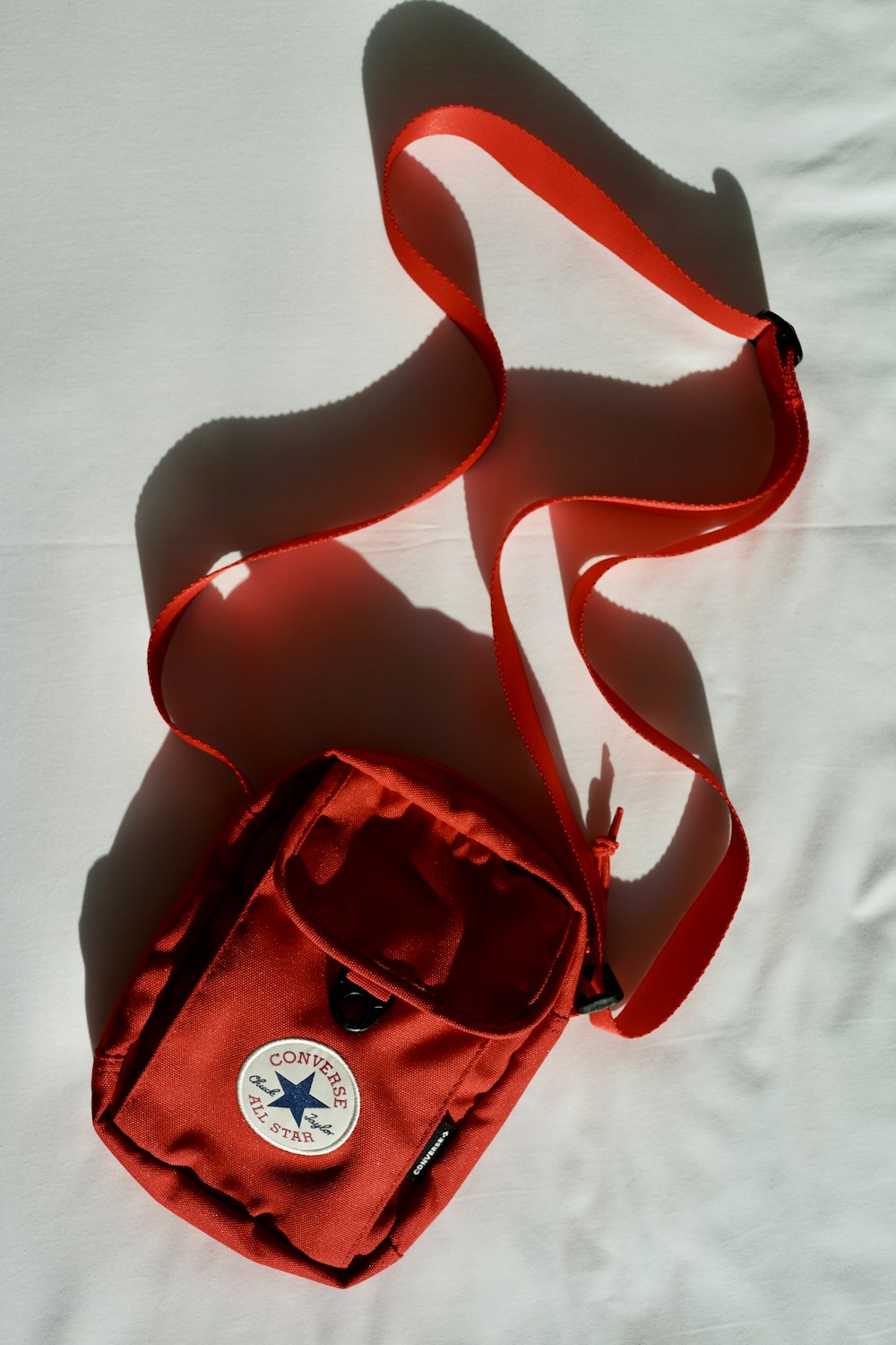 a red bag laying on top of a white sheet