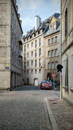 a red car is parked on a cobblestone street