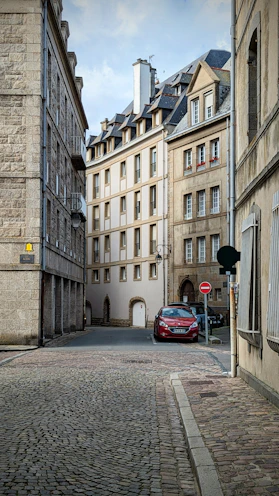 a red car is parked on a cobblestone street