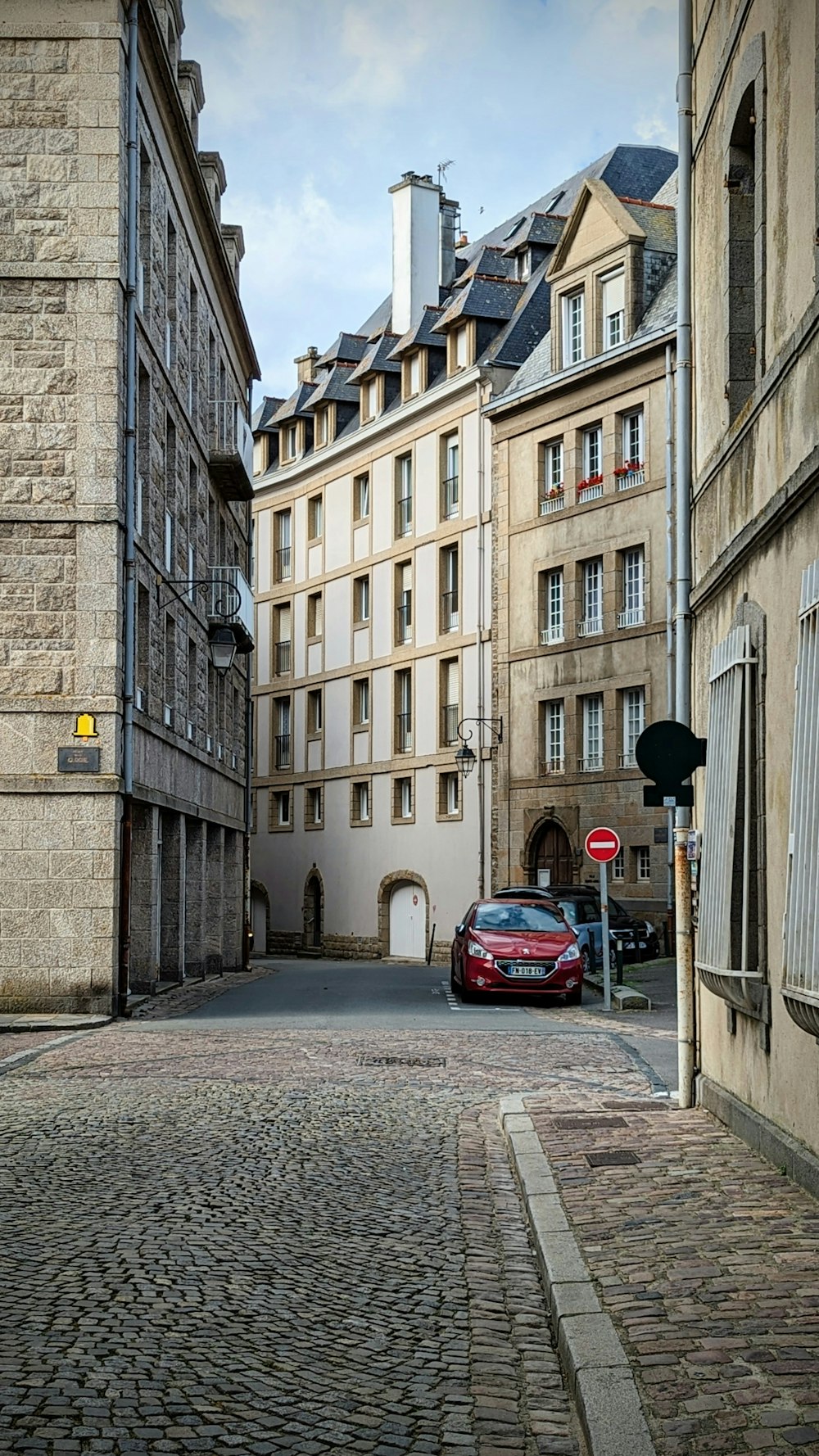 a red car is parked on a cobblestone street