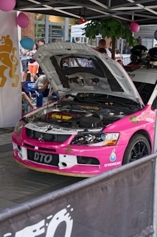 a pink car with a hood open in a showroom