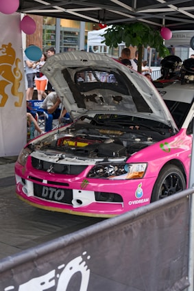 a pink car with a hood open in a showroom