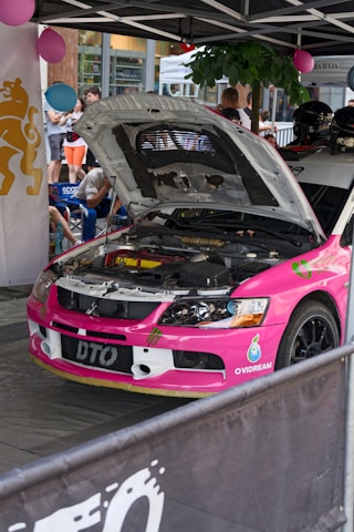 a pink car with a hood open in a showroom