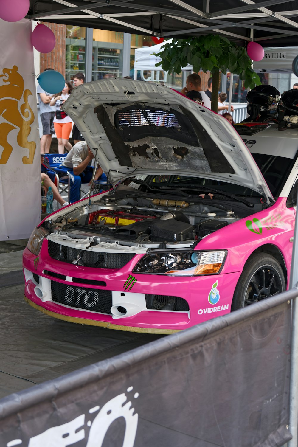 Une voiture rose avec un capot ouvert dans une salle d’exposition