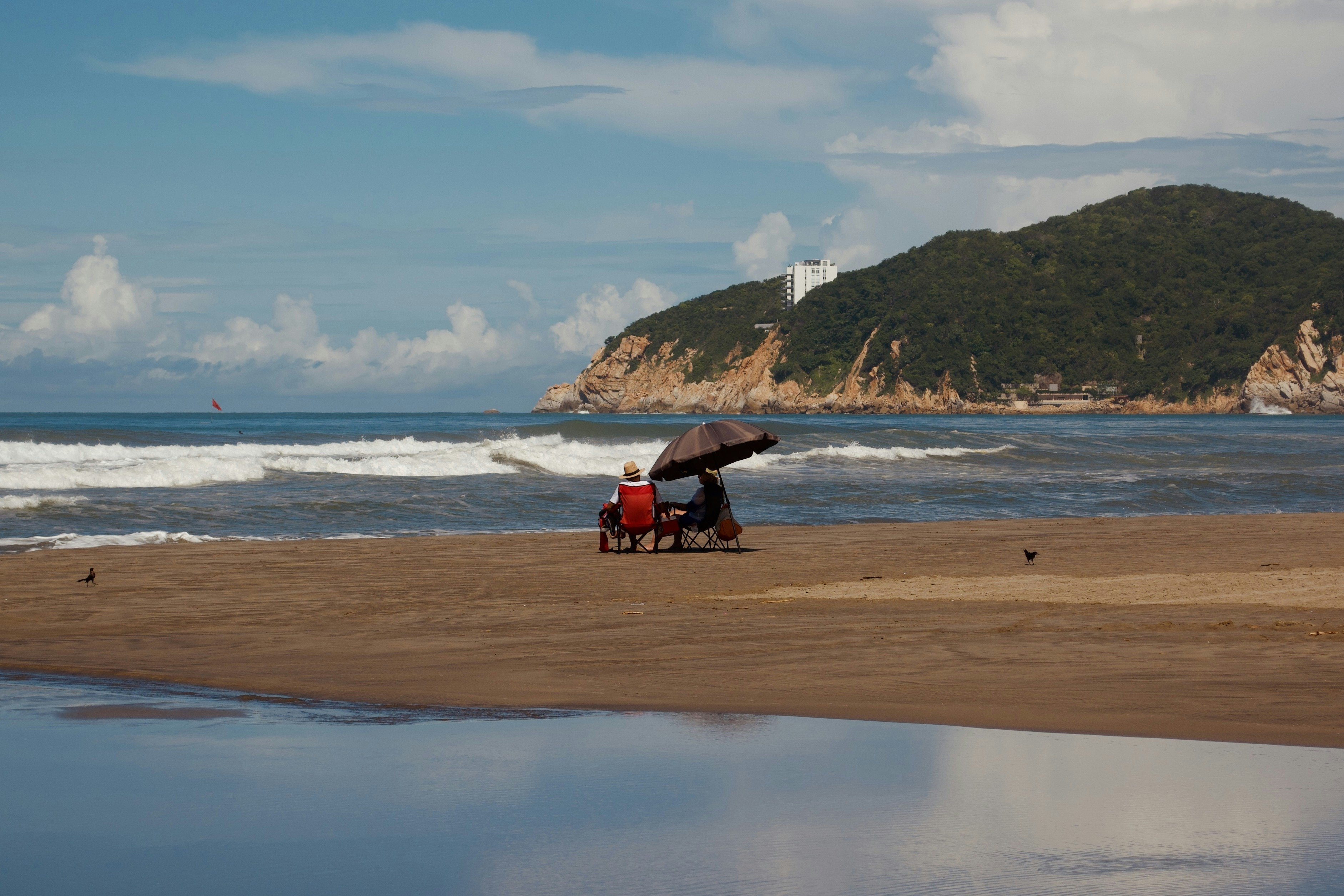 two people sitting under an umbrella on a beach