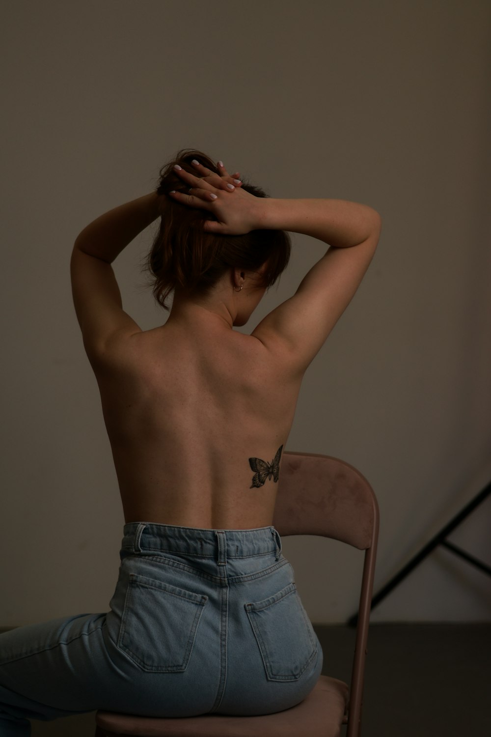 a woman with a tattoo on her back sitting on a chair