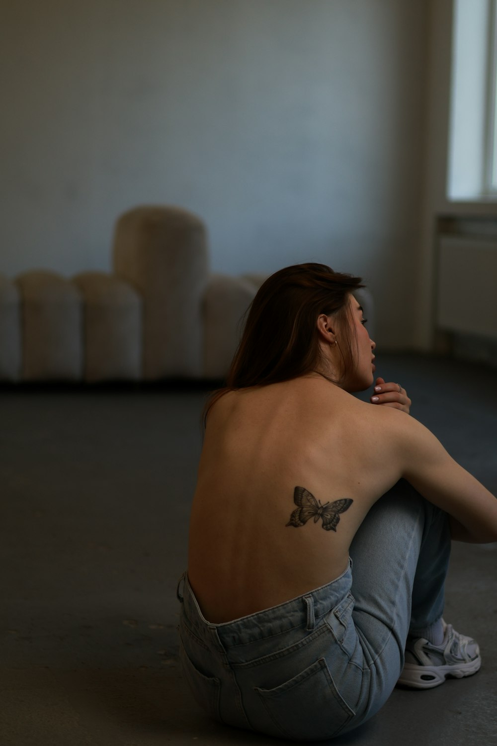 a woman sitting on the floor with a butterfly tattoo on her back