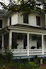 Cozy coastal house exterior bathed in warm sunlight with welcoming front porch.