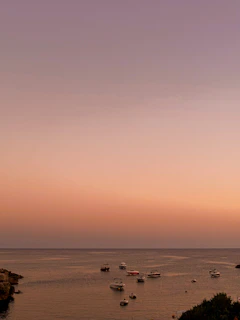 Sunrise over a tranquil bay with fishing boats gently rocking on the water.