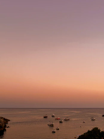 Sunrise over a tranquil bay with fishing boats gently rocking on the water.