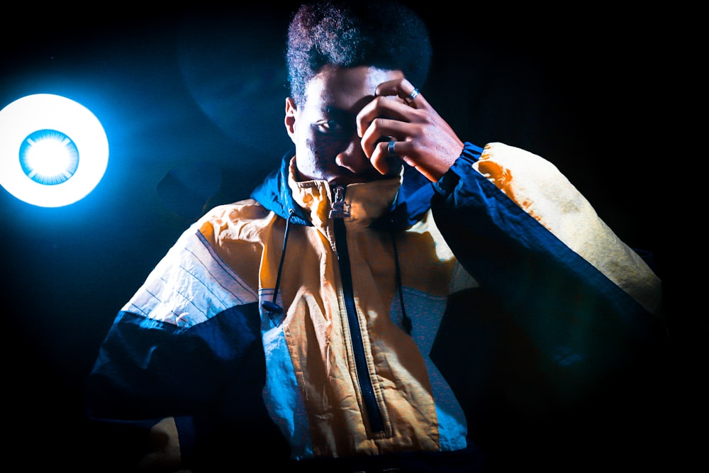 a man in a yellow and blue jacket holding a light