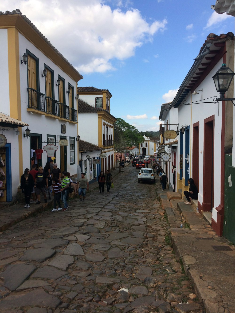 a cobblestone street lined with white and yellow buildings