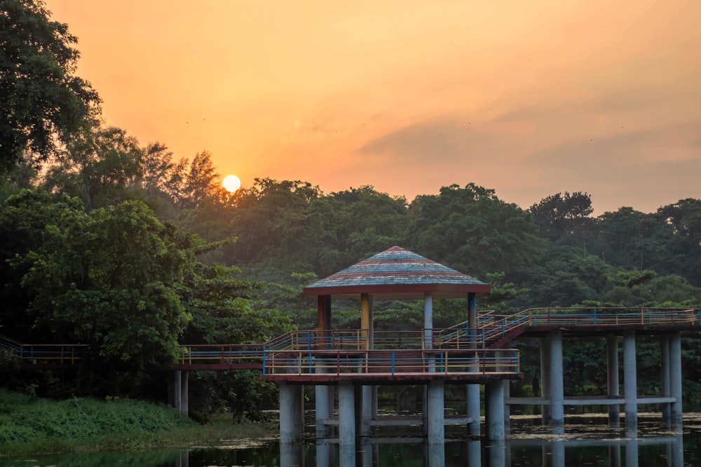 a gazebo sitting on top of a lake next to a forest