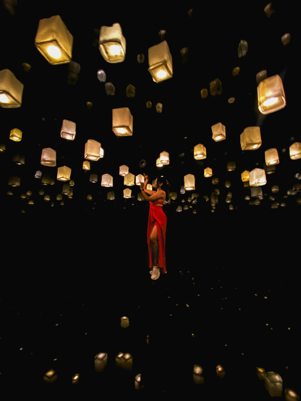 a woman in a red dress is surrounded by lanterns