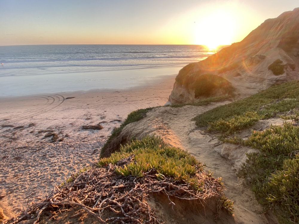 the sun is setting over the ocean on the beach