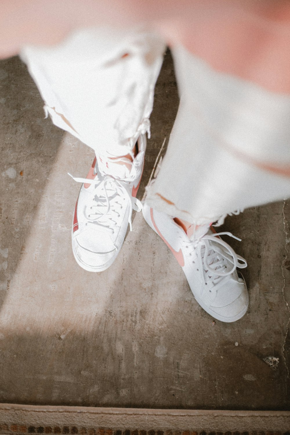 a person wearing white shoes standing on a wooden floor