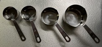 Close-up of sleek measuring cups and spoons with clear markings on a marble surface.