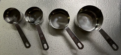 A set of precision measuring spoons and cups arranged neatly on a marble surface.