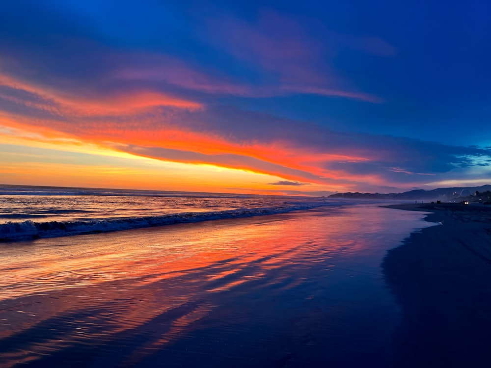 a sunset on a beach with waves coming in