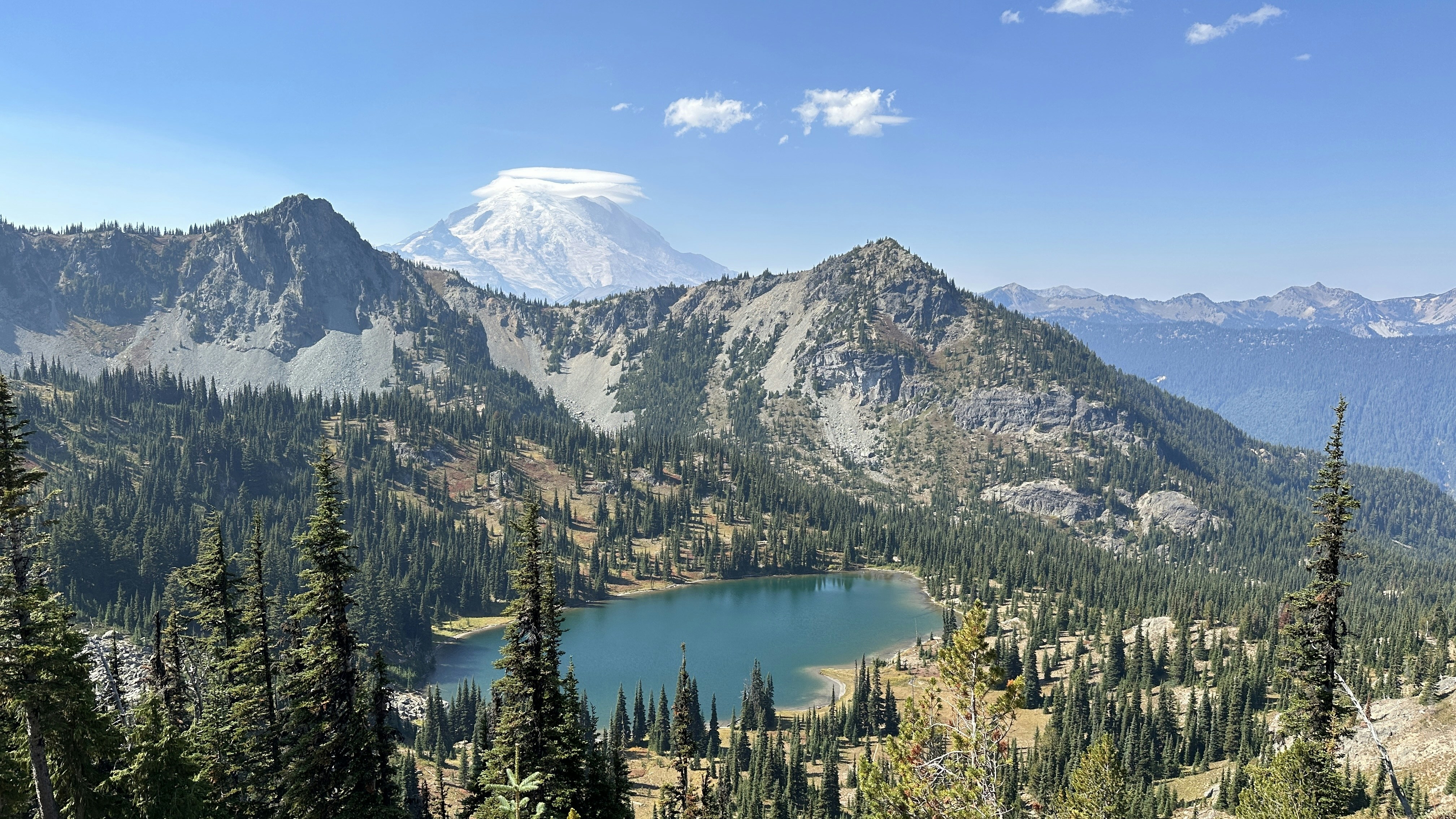 a mountain range with a lake surrounded by trees