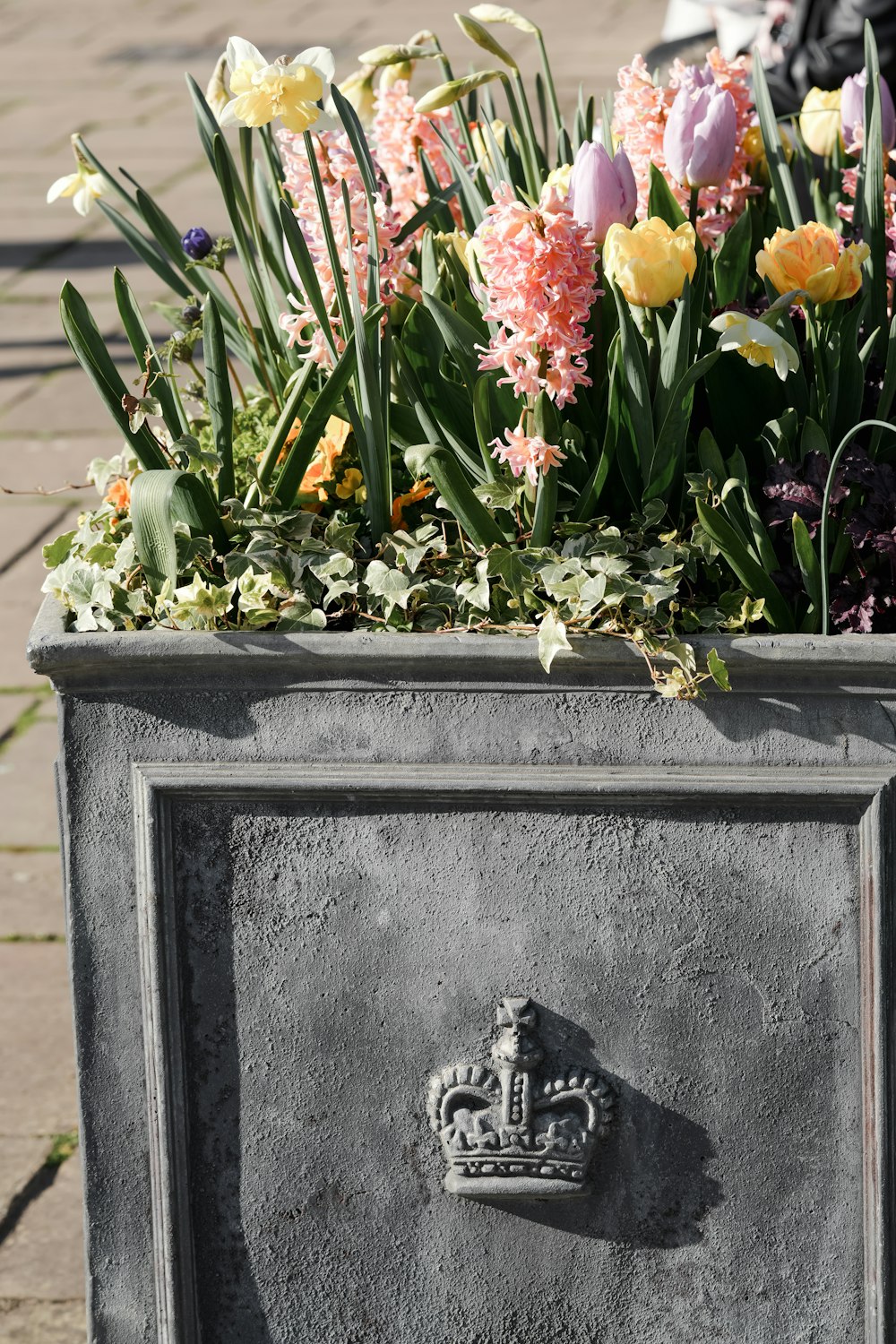 a planter with flowers in it sitting on a sidewalk