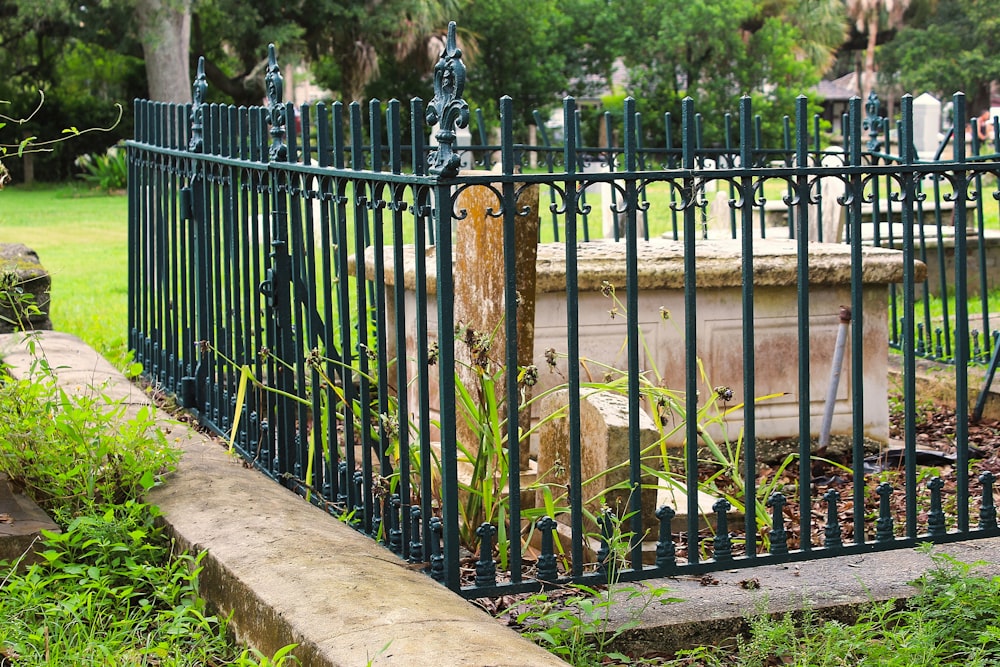 a cemetery with a green iron fence surrounding it