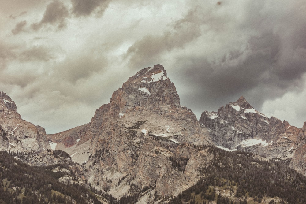 the mountains are covered in snow under a cloudy sky