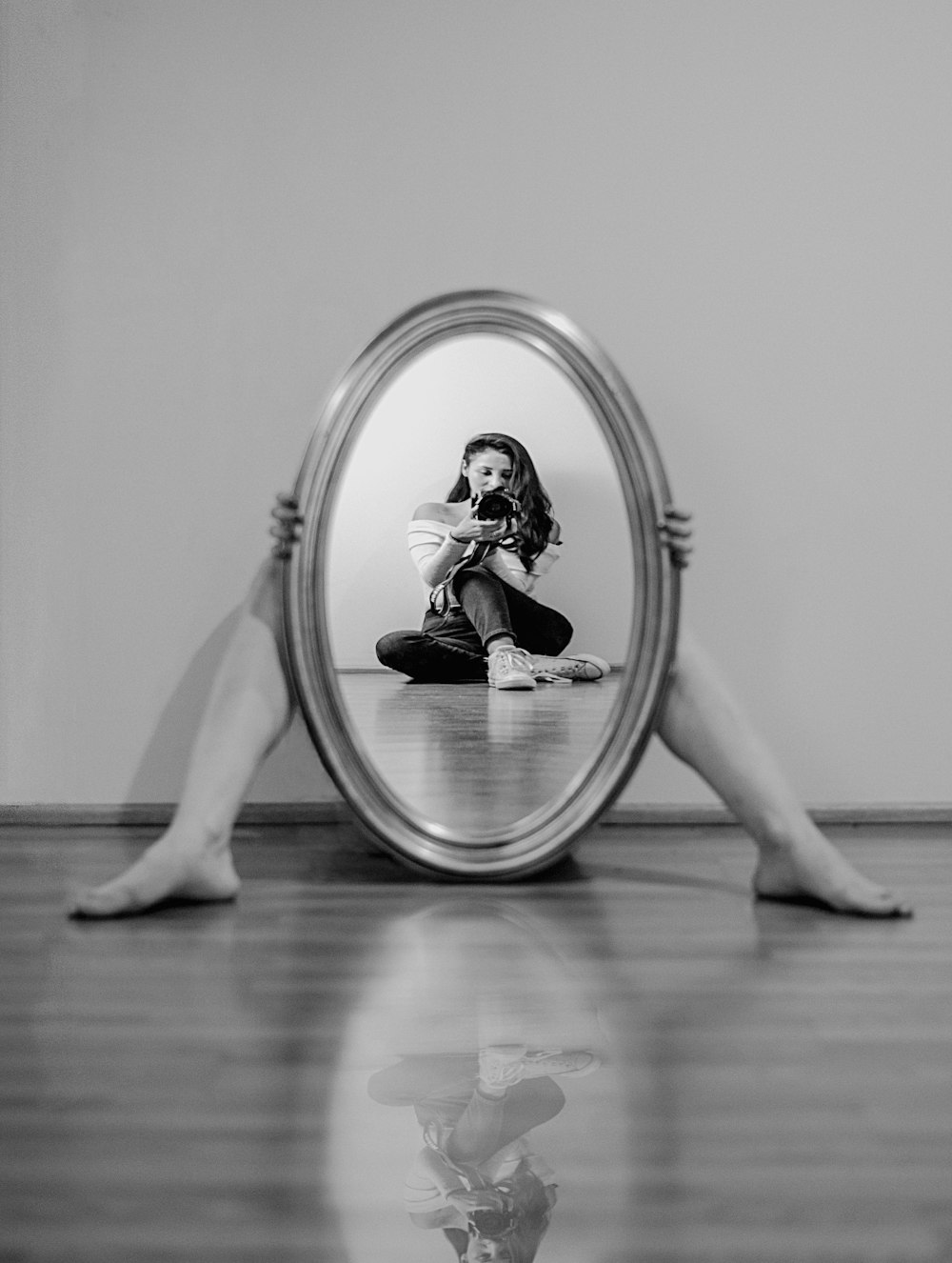 a woman sitting on the floor looking at her reflection in a mirror