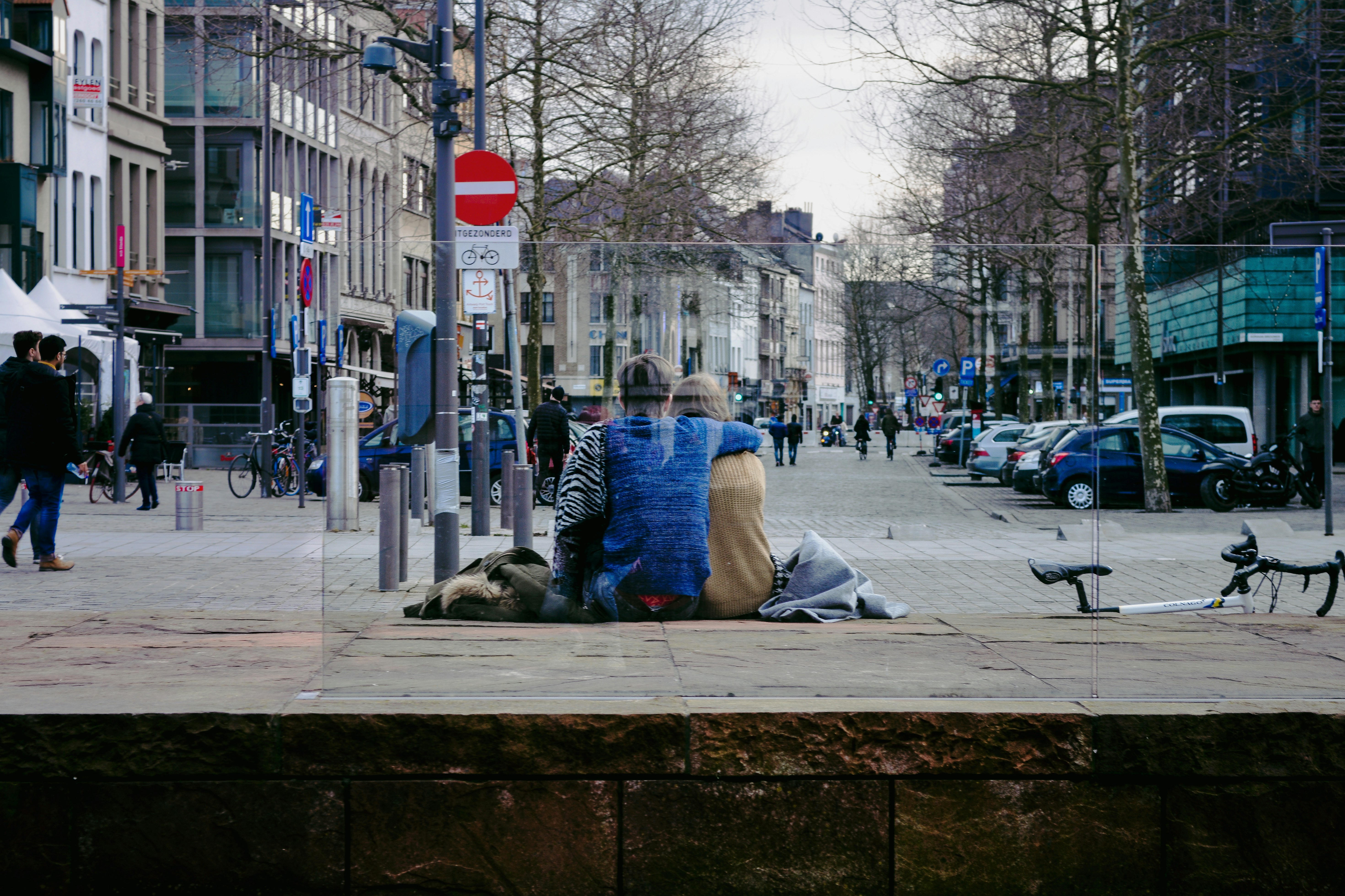 a couple of people sitting on top of a sidewalk