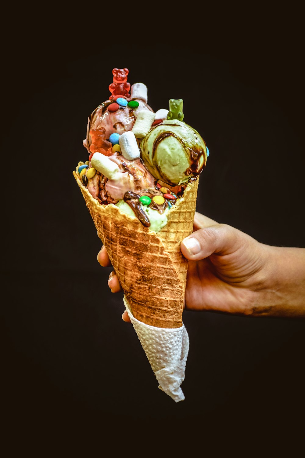 a hand holding an ice cream cone filled with lots of toppings