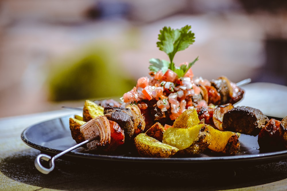 a black plate topped with meat and vegetables