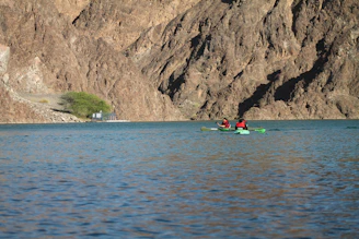 A serene kayak gliding through calm waters framed by towering cliffs.