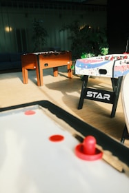 Indoor games room featuring billiards and air hockey tables with warm lighting.