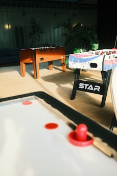 A warmly lit indoor games room featuring a billiards table and air hockey setup.