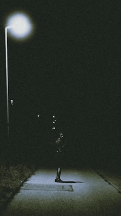 A shadowy image of Freddy Krueger standing beneath a flickering streetlamp on Elm Street at night.