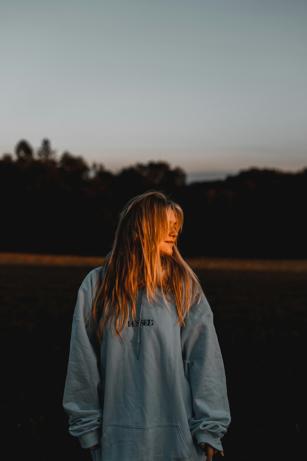 a woman with long hair standing in a field