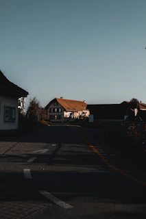 A quiet village street bathed in warm afternoon light, showing daily life in subtle detail.