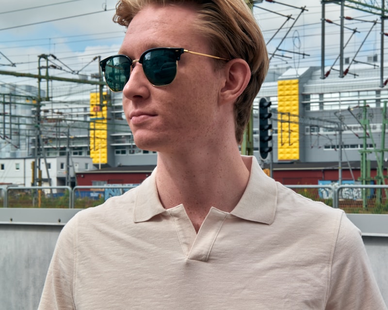 a man wearing sunglasses standing in front of a train