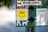 A collection of stickers and signs are attached to a surface, featuring a prominent yellow circular sticker with 'VHS is Happiness' written on it. Other elements include a white sticker advertising sustainable dog treats, a logo for a clothing company called 'way.vee,' and silhouettes of a person walking a dog.