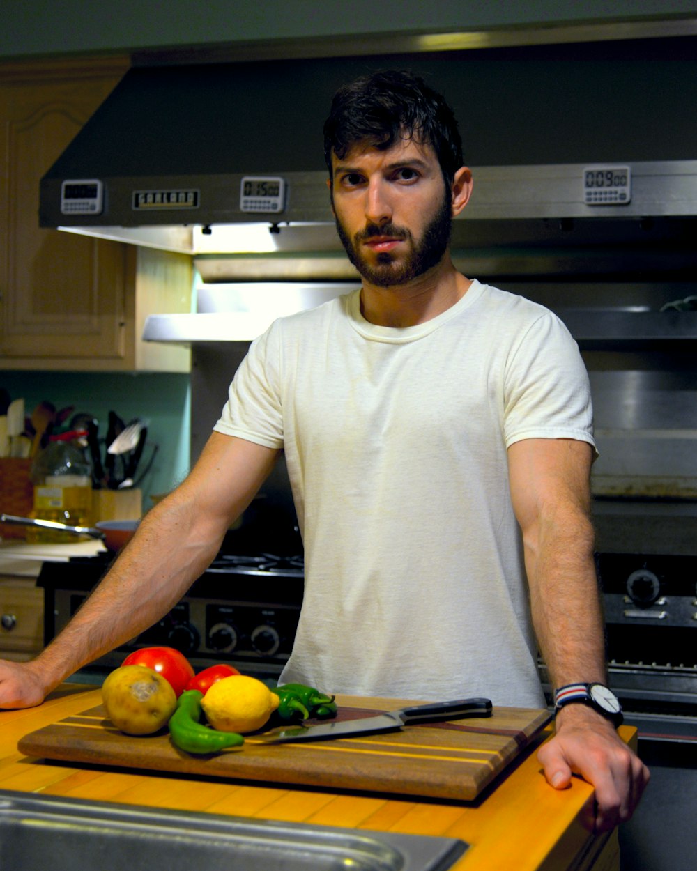 a man standing in a kitchen next to a cutting board