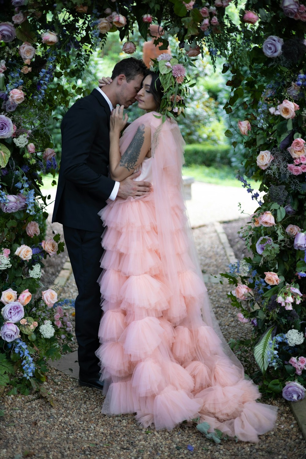 a man and a woman standing under a floral arch