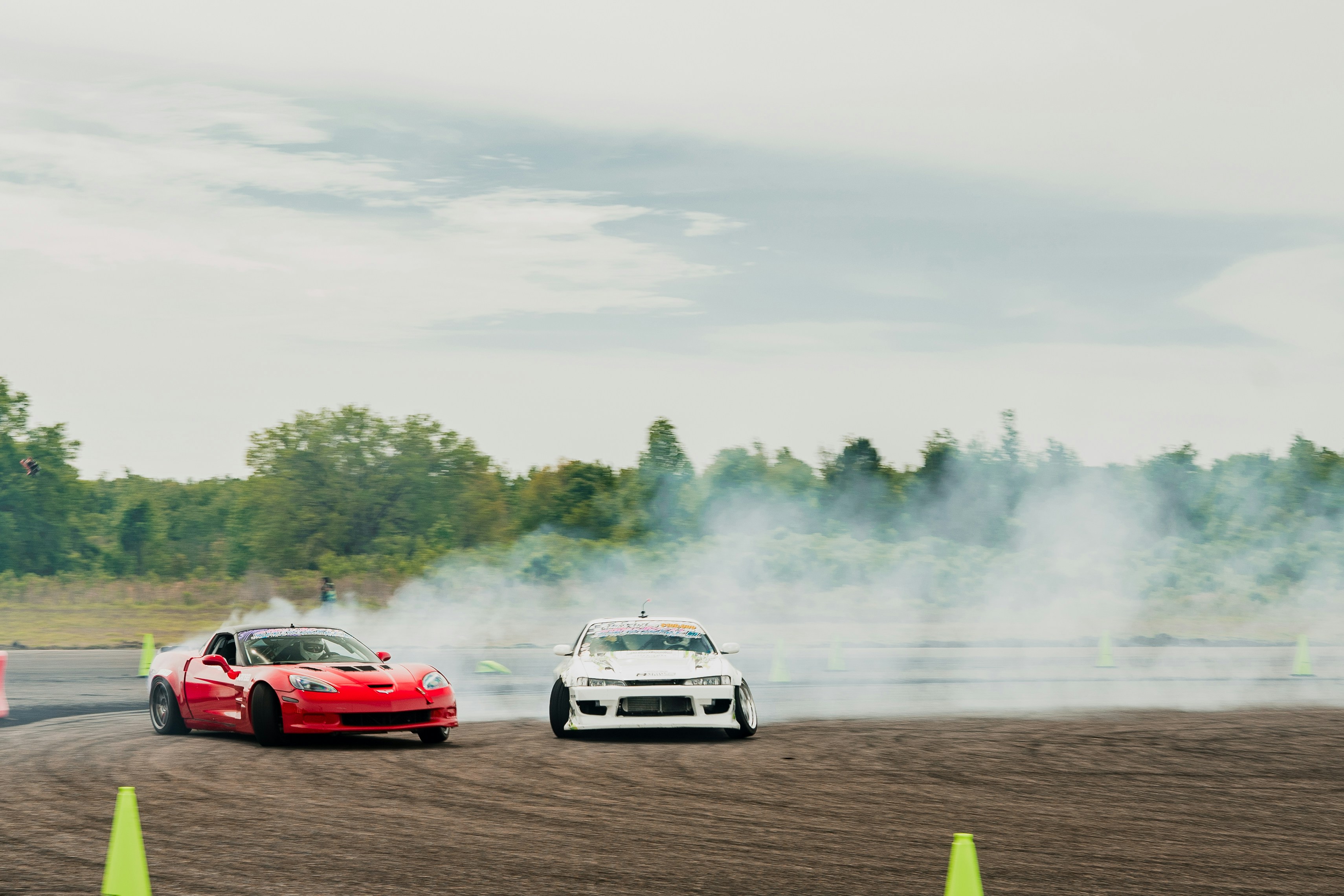 a couple of cars driving down a dirt road